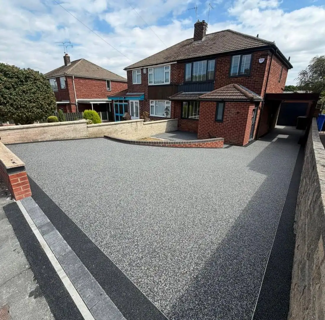 Grey resin bound driveway behind a brick wall